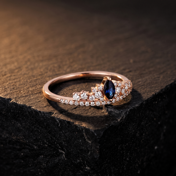 The Coronet Ring, a marquise sapphire tiara with diamond crown clusters in rose gold, on dark stone