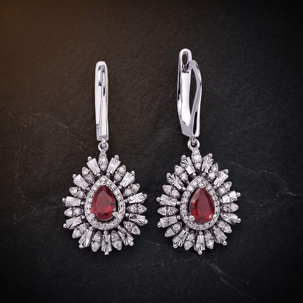 The Lantern Earrings on dark stone, pear cut rubies in diamond halos inside engraved rays, on lever backs