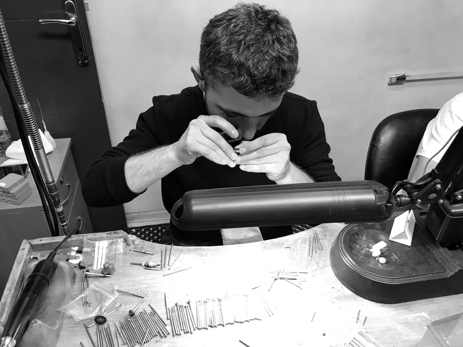 Kadir at the bench, loupe to his eye, inspecting a ring