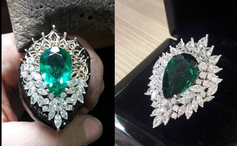 The same emerald ring, held in fingers at the bench and finished in its box