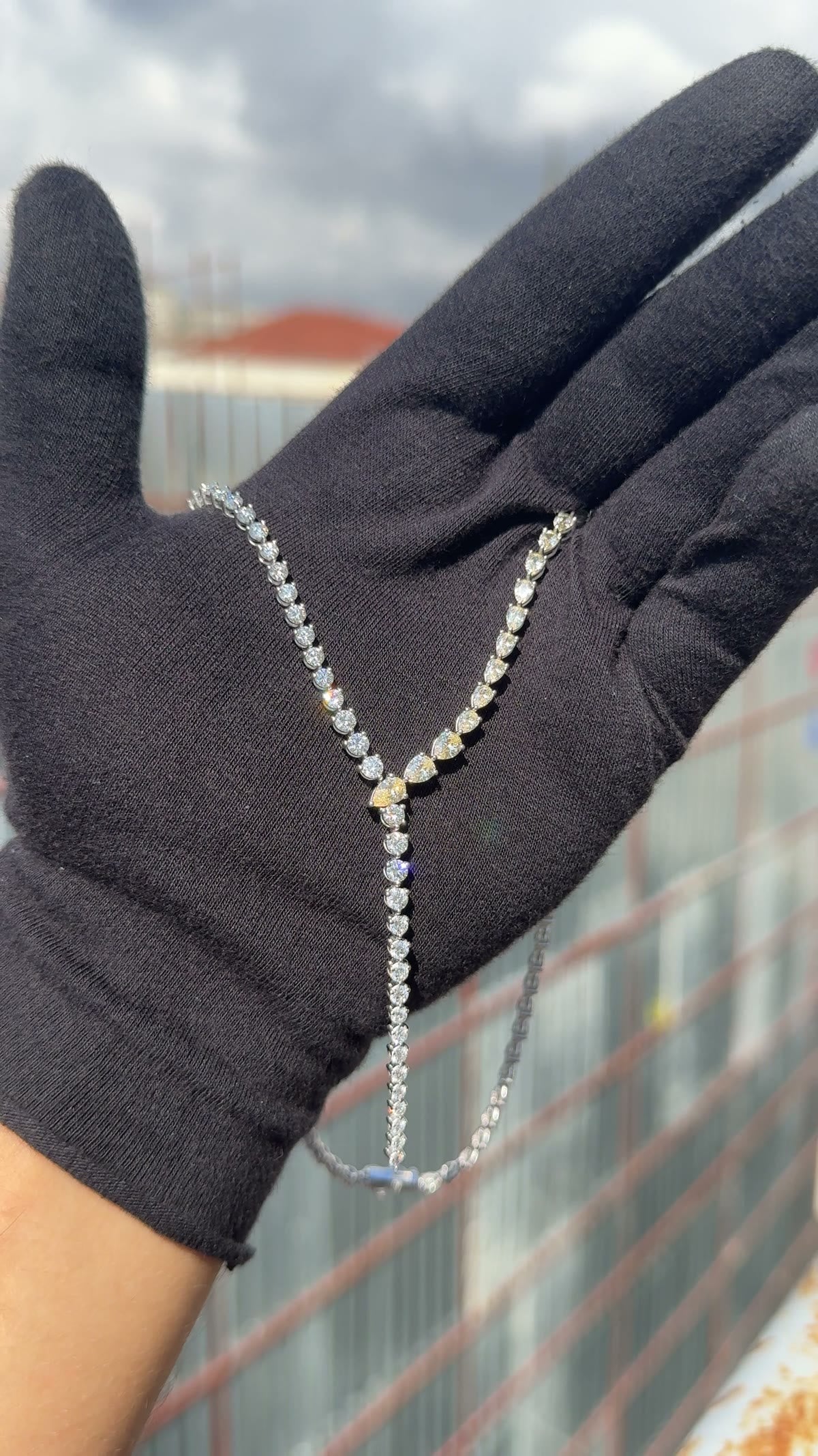 Lariat of yellow and white pear-cut diamonds across a gloved hand