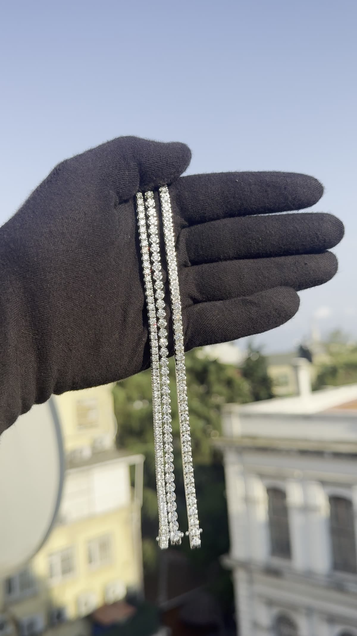 Three diamond strands of different weights held in a gloved hand