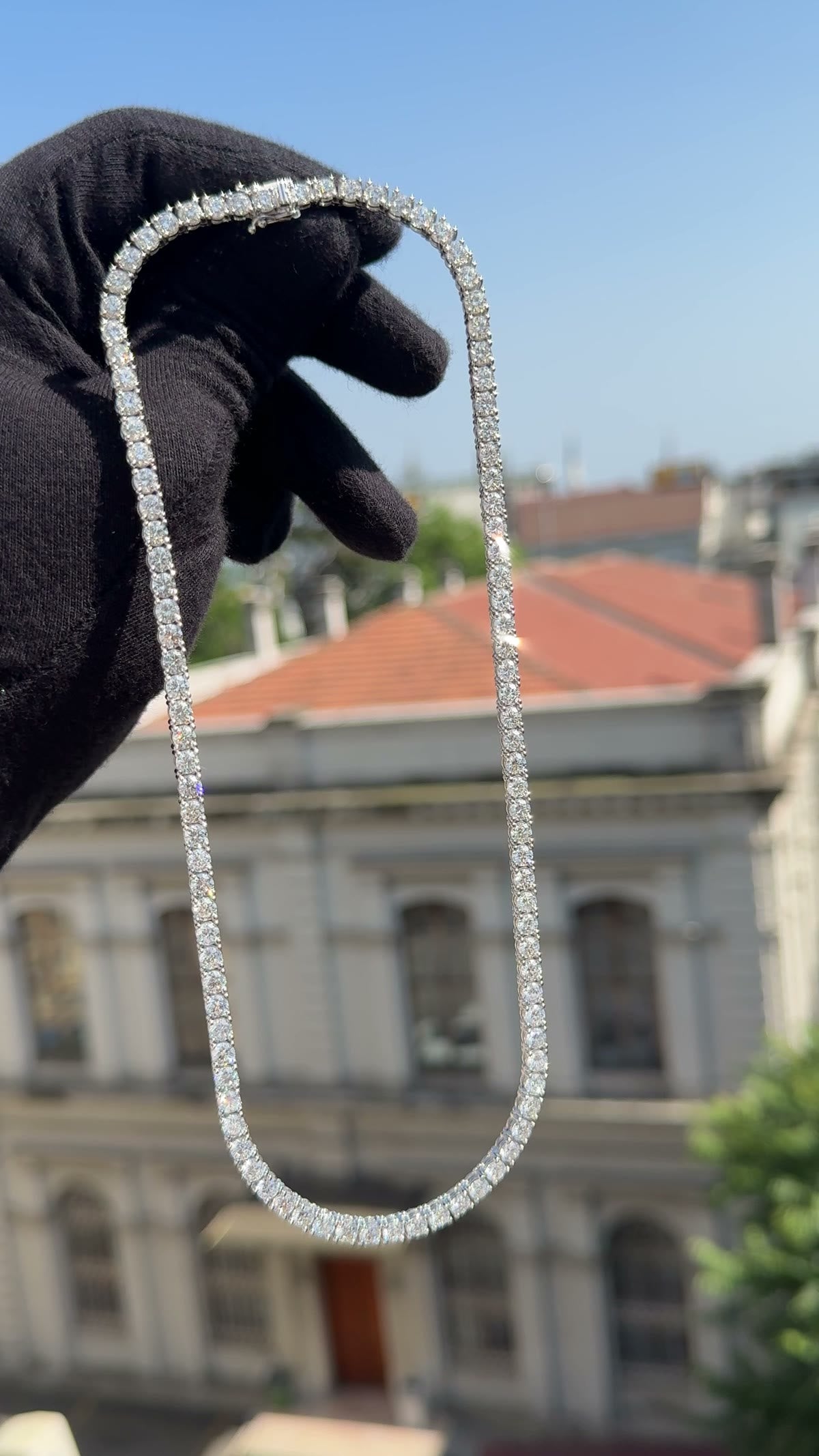 Diamond line necklace held open in a gloved hand