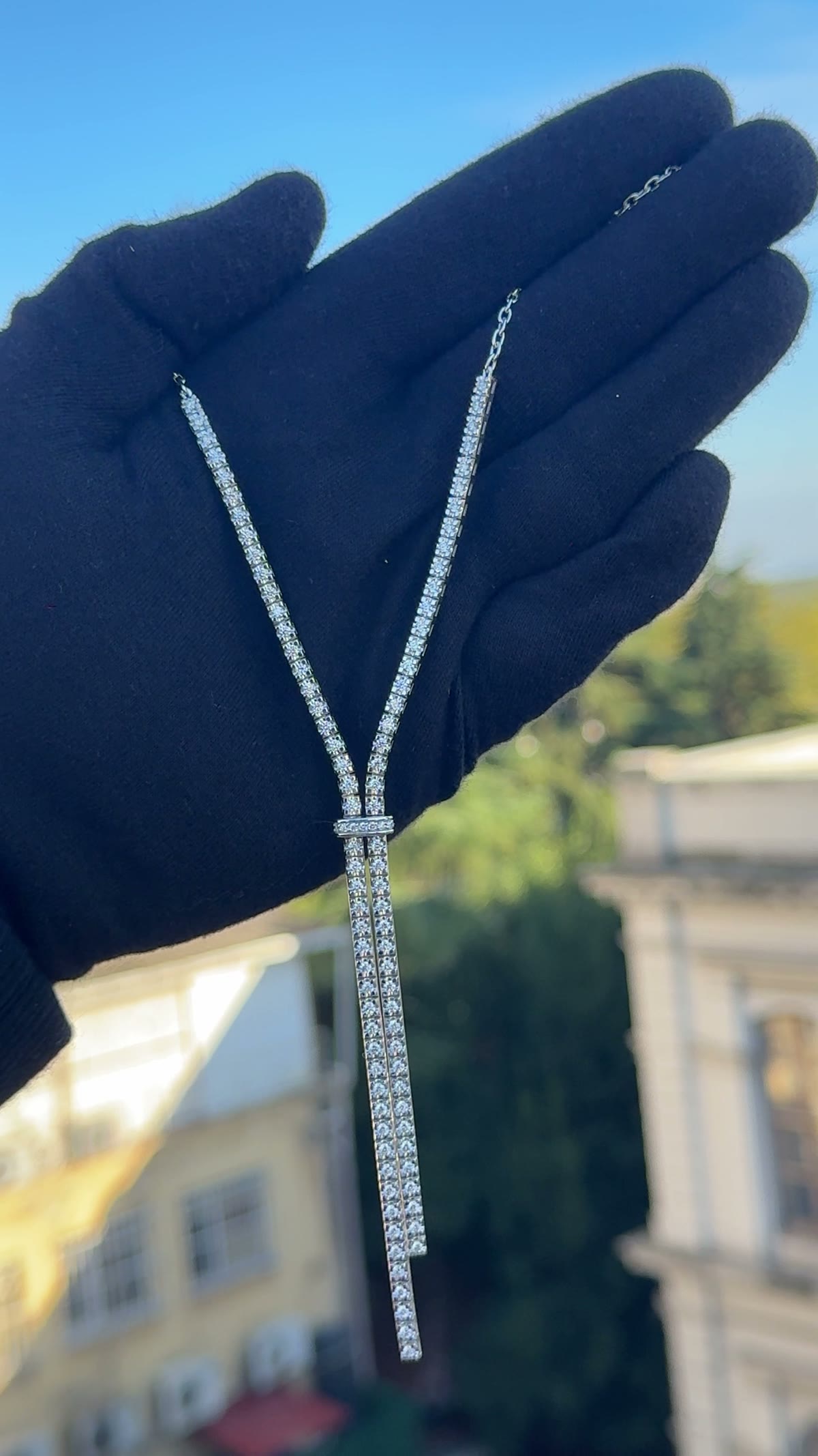 Y-drop tassel necklace hanging from a gloved hand